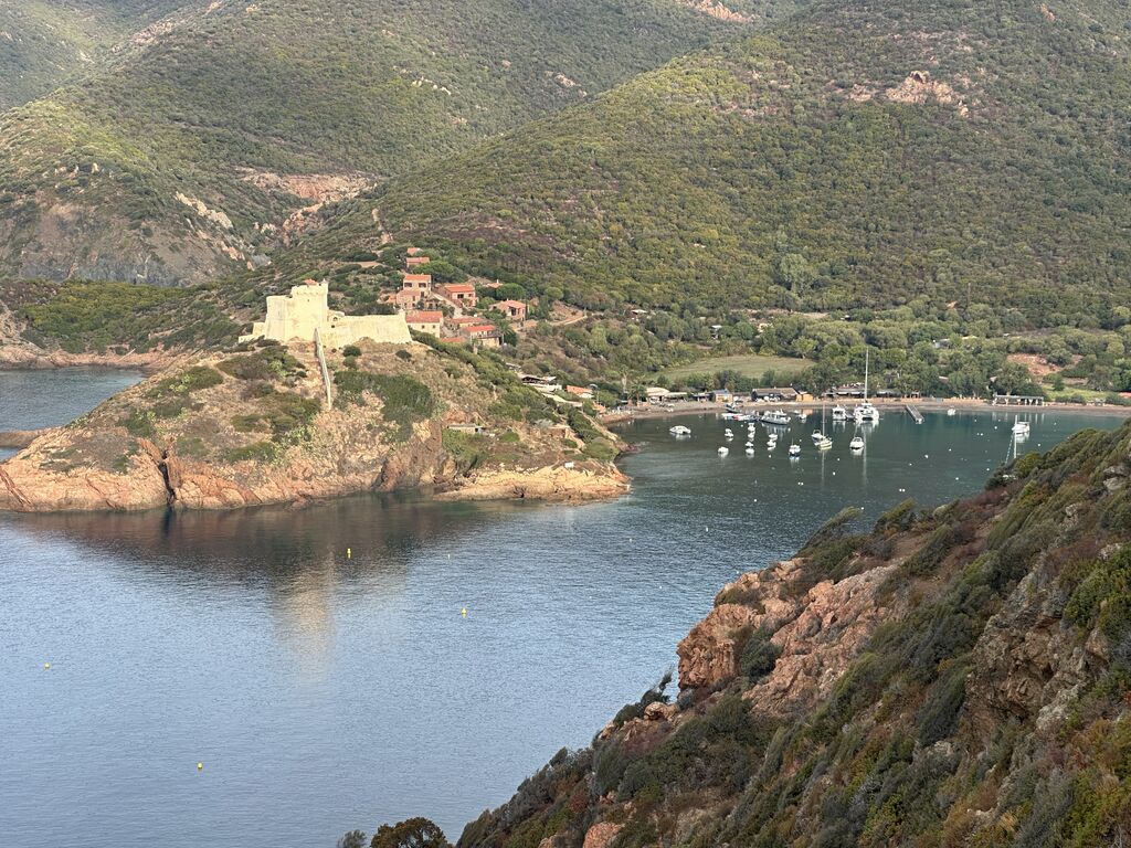 Le golfe de Girolata vu d'en haut : le fort génois sur sa presqu'île, les bateaux au mouillage et les montagnes