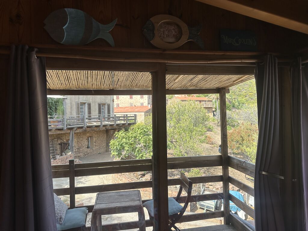 La terrasse couverte du studio, ses chaises et les maisons de pierre du village
